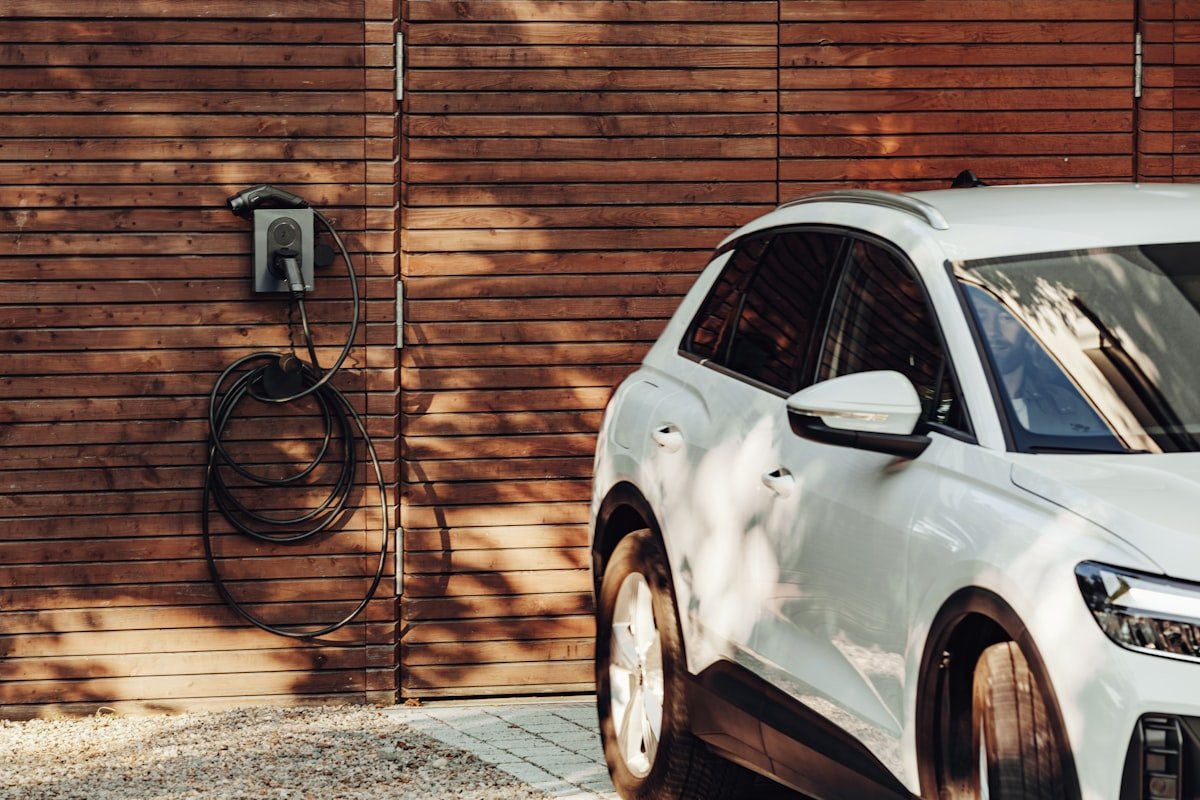 White electric car parked at home with Level 2 EV charger installed on wall